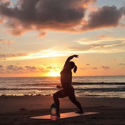 Silhouette of a person in a dynamic yoga pose at sunrise.